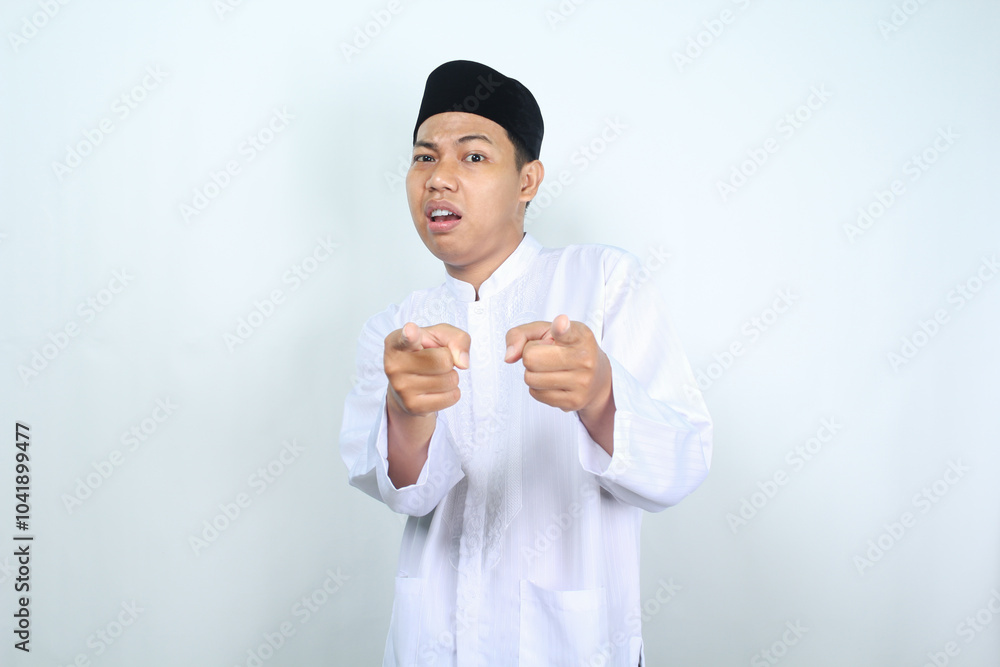 confused asian muslim man pointing at camera isolated on white background confused asian muslim man pointing at camera isolated on white background