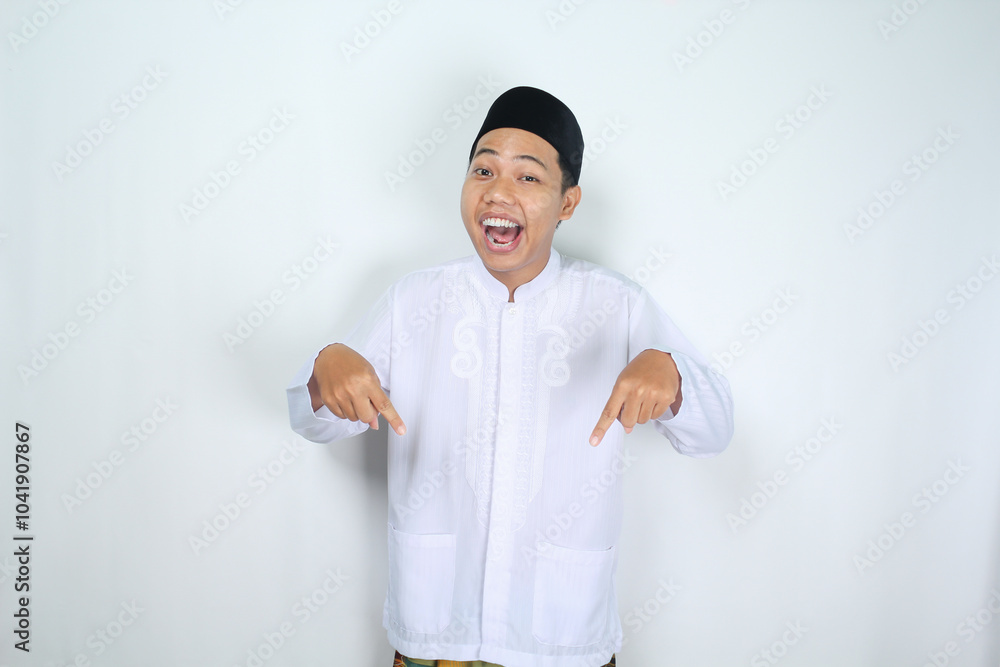 attractive muslim asian man pointing down and shouting with mouth open isolated on white background attractive muslim asian man pointing down and shouting with mouth open isolated on white background