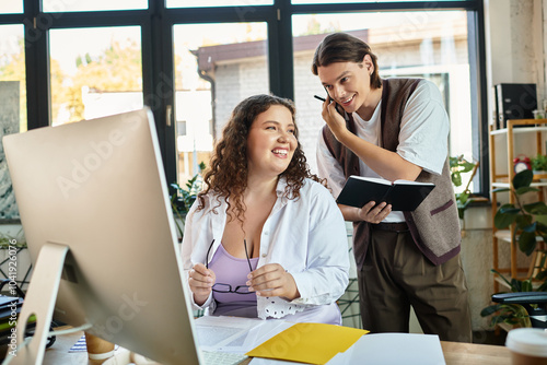 A young plus size woman smiles at her male friend in office.
