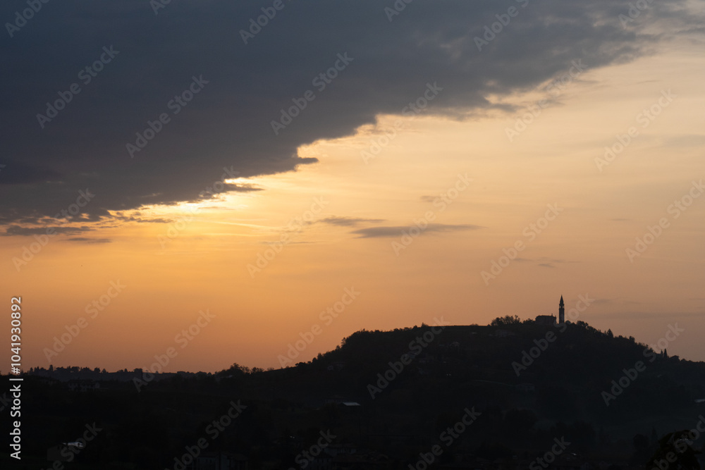 La silhouette del borgo di Formeniga, in provincia di Treviso, Veneto, Italia, contro il cielo arancione all'alba di un giorno d'autunno, lungo il cammino delle colline del Prosecco La silhouette del borgo di Formeniga, in provincia di Treviso, Veneto, Italia, contro il cielo arancione all'alba di un giorno d'autunno, lungo il cammino delle colline del Prosecco