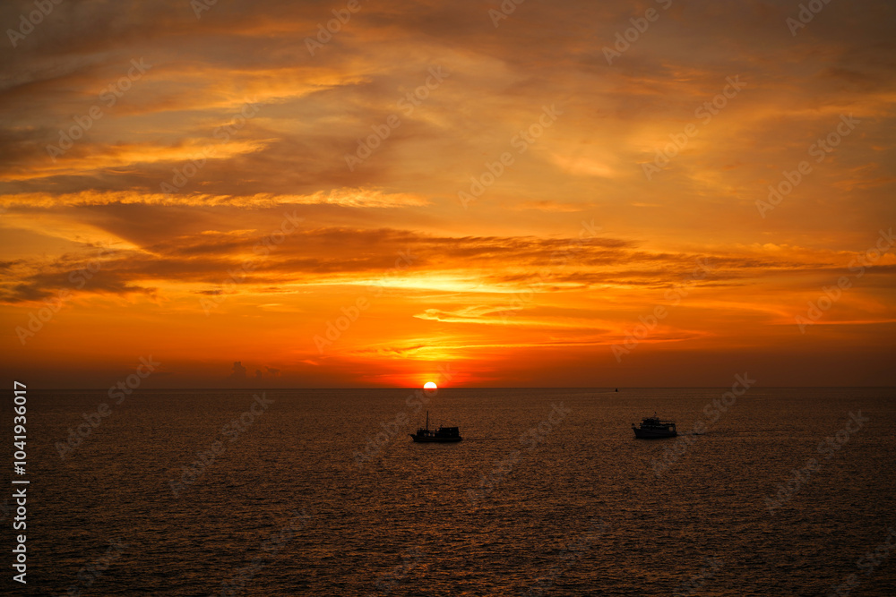 Breathtaking sunset scene, tourist boat in beautiful seascape and sky reflecting on the tranquil waters, creating a serene and picturesque setting.High view form Promthep Cape, Phuket, Thailand. Breathtaking sunset scene, tourist boat in beautiful seascape and sky reflecting on the tranquil waters, creating a serene and picturesque setting.High view form Promthep Cape, Phuket, Thailand.