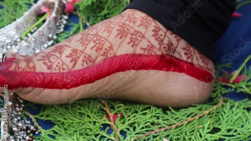 A married woman applying mahavar (red color) on the side of her foot during Karwa Chauth, symbolizing a positive and strong marital bond photo