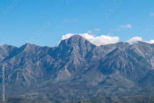 Scenic view of majestic Ceraunian mountain range in Albania, with clear blue sky above the peak. slopes are covered in lush green vegetation. Hiking and outdoor activities in Albanian Alps. Wanderlust photo