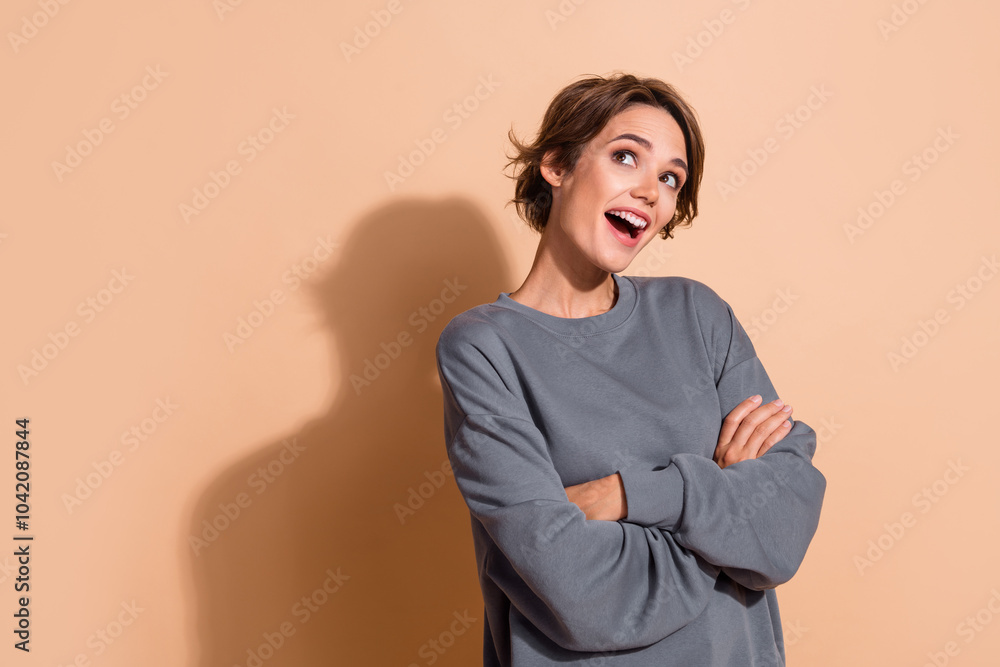 Photo portrait of lovely young lady folded hands look excited empty space wear trendy gray garment isolated on beige color background Photo portrait of lovely young lady folded hands look excited empty space wear trendy gray garment isolated on beige color background