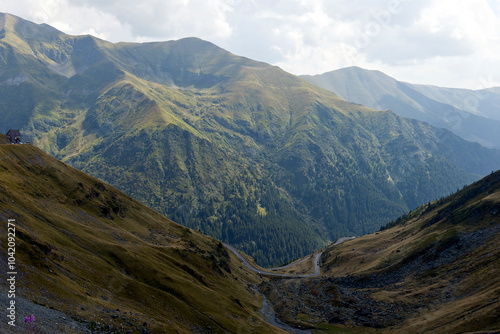 A breathtaking panoramic view of the Carpathian Mountains in Romania, featuring a stretch of the Transfăgărășan Highway winding through the valley. 