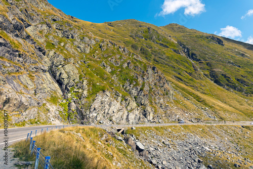 A breathtaking panoramic view of the Carpathian Mountains in Romania, featuring a stretch of the Transfăgărășan Highway winding through the valley. 