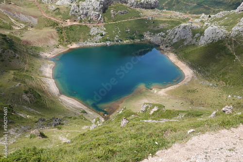 Aerial view of La Cueva Lake in Saliencia, Somiedo Park, featuring blue waters, green hills, and a sandy shoreline. photo