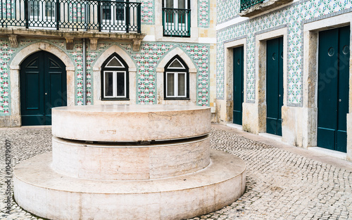 A traditional old portuguese house decorated with flowery fizzes in a historic neighborhood of Lisbon, Portugal. In the courtyard there is a historical memorial round formation.
