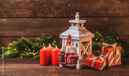 Obraz na płótnie Merry Christmas greetings. Knitting mittens with ornaments, Lantern with candles, red candles and fir branches on a dark wooden background w salonie