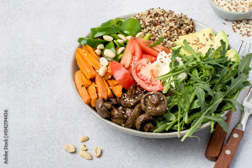 Buddha bowl made from quinoa, avocado, carrots, arugula, cream cheese, mushrooms and nuts. Healthy food, full bowl. Vegetarian dish. Top view horizontal.