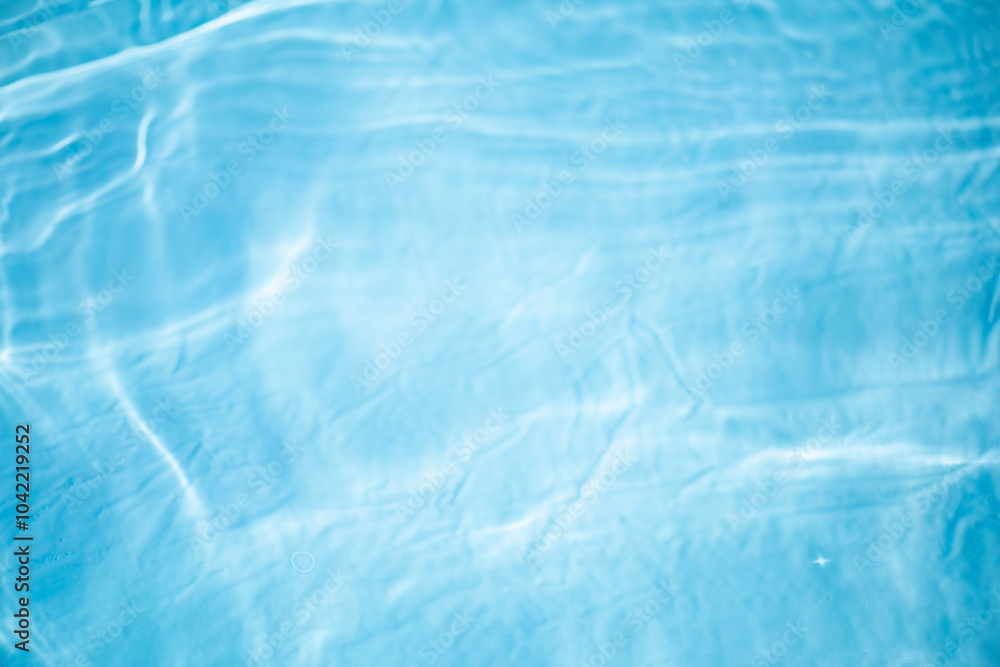 Obraz premium Blue water with ripples on the surface. Defocus blurred transparent blue colored clear calm water surface texture with splashes and bubbles. Water waves with shining pattern texture background.