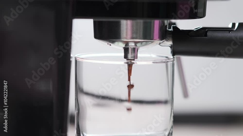 Coffee pours from the holder into a transparent glass cup. Making coffee in a coffee machine. Espresso. Making coffee at home

