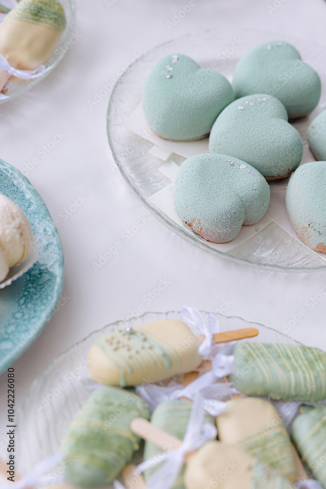 Delicate heart-shaped desserts and colorful popsicles arranged on elegant plates for a celebration Delicate heart-shaped desserts and colorful popsicles arranged on elegant plates for a celebration