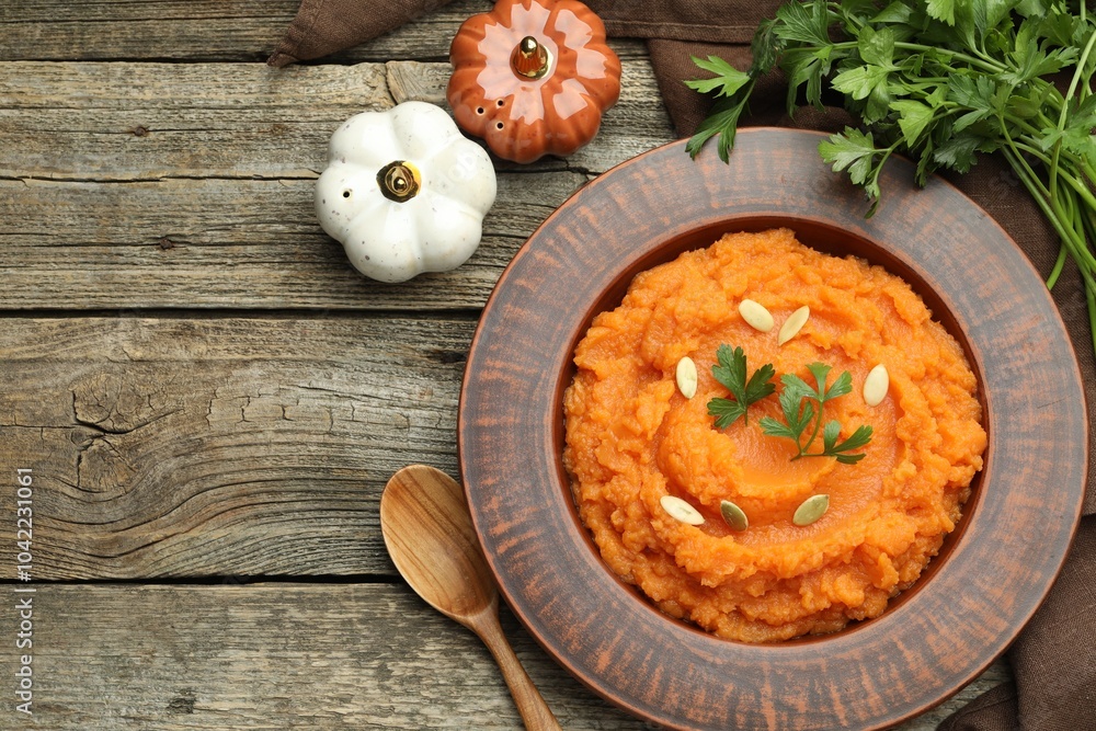 Tasty mashed sweet potato with pumpkin seeds in bowl, parsley and spices on wooden table, flat lay. Space for text Tasty mashed sweet potato with pumpkin seeds in bowl, parsley and spices on wooden table, flat lay. Space for text