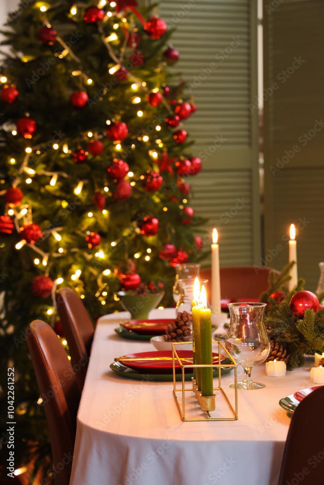 Obraz premium Festive table setting with Christmas decorations and burning candles in dining room