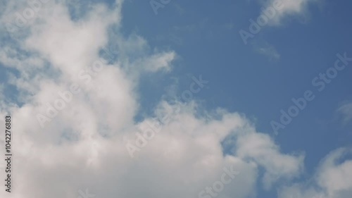 White clouds moving fast across blue summer sky, time lapse footage in 4K