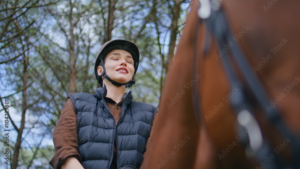 Jockey woman sitting horse at woods portrait. Happy smiling model looking camera Jockey woman sitting horse at woods portrait. Happy smiling model looking camera