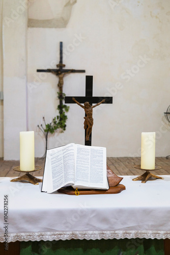 A church altar with a cross, candles, flowers, and an open bible