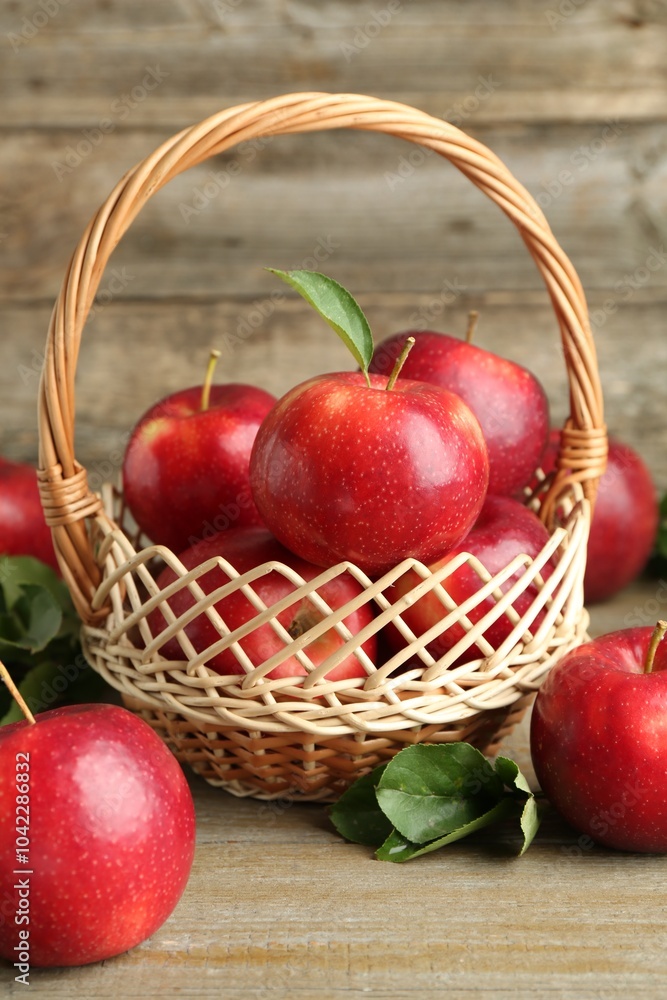 Fresh ripe red apples in wicker basket on wooden table Fresh ripe red apples in wicker basket on wooden table