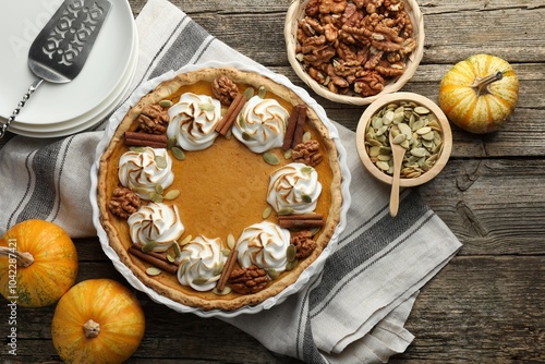 Tasty homemade pumpkin pie in baking dish and ingredients on wooden table, flat lay