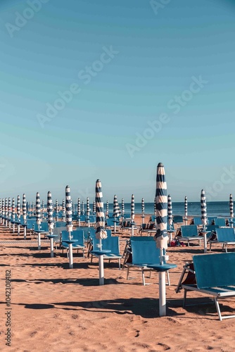 Typical Italian Adriatic Riviera beach near Fano and Marotta, Marche. Rows of blue sunbeds and umbrellas. Vintage vacation atmosphere.