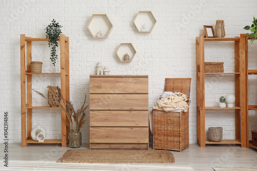 Foto Interior of light laundry room with clothes basket, wooden dresser and shelving