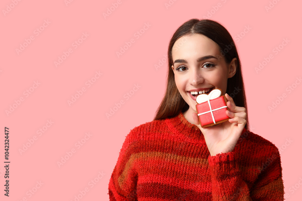 Young woman with tasty Christmas gingerbread cookie on pink background Young woman with tasty Christmas gingerbread cookie on pink background