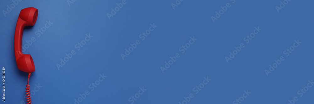 Red corded telephone handset on blue background, top view. Banner design with space for text Red corded telephone handset on blue background, top view. Banner design with space for text