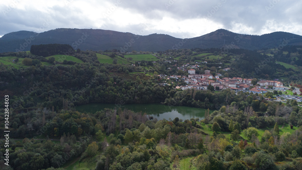 Obraz premium Lago y pueblo en las montañas verdes.