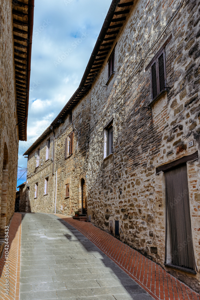 The narrow alleyways of Collemancio reveal beautifully preserved medieval architecture set against the backdrop of a clear blue sky in Umbria. Village Collemancio - Italian national heritage