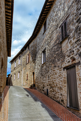 The narrow alleyways of Collemancio reveal beautifully preserved medieval architecture set against the backdrop of a clear blue sky in Umbria. Village Collemancio - Italian national heritage