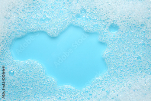 Washing laundry. White foam with bubbles on light blue background, top view photo