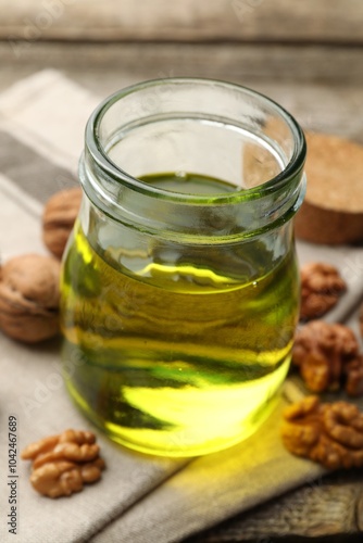 Cooking oil in jar and walnuts on table, closeup