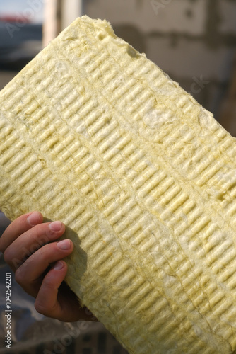 Close-up of male hands holding a piece of wool insulation . Insu photo