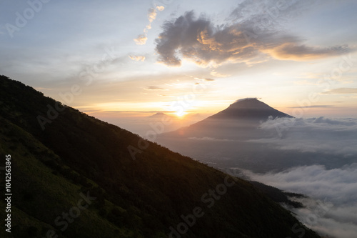 A breathtaking sunrise over two majestic volcanoes with dramatic clouds. Perfect for travel, adventure, and nature themed projects. photo