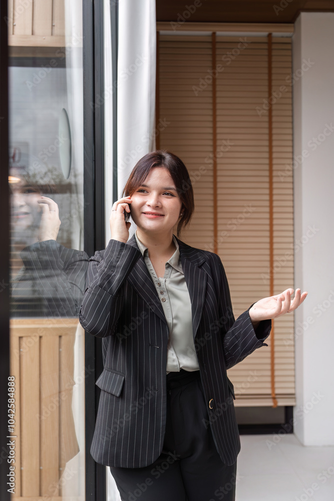 Confident Business Woman in Professional Attire Standing by Window in Modern Office Setting Confident Business Woman in Professional Attire Standing by Window in Modern Office Setting