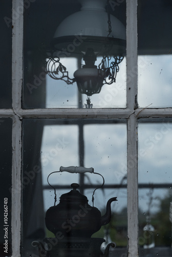 Dark silhouettes of antique kettle and lamp in  window of a cottage in Marken Haven photo