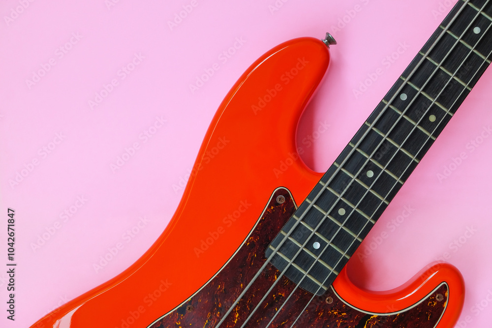 Obraz premium Red electric bass guitar on a pink background. Close-up image.