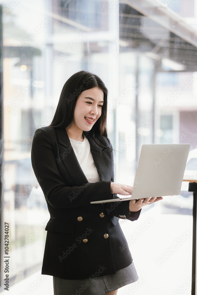 Fototapeta premium Beautiful Asian businesswoman talking on the phone using laptop in office