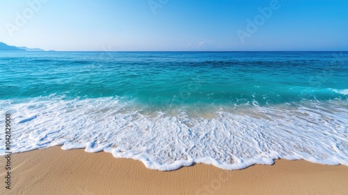 Wallpaper Mural A serene beach scene featuring clear blue water lapping gently against golden sand under a bright, cloudless sky. Torontodigital.ca
