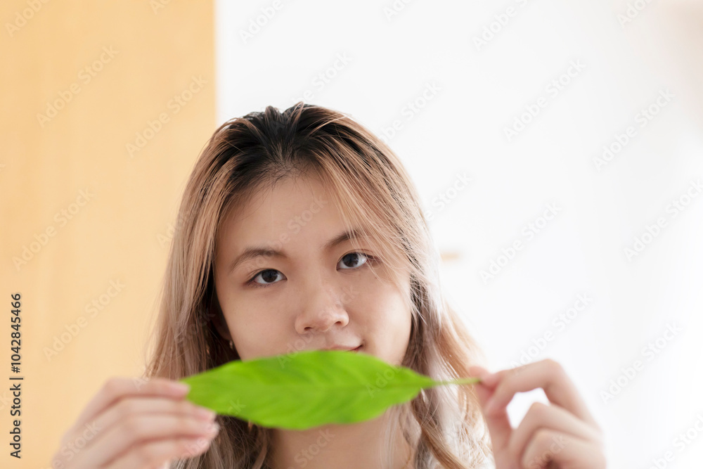 Young chinese woman holding green leave in an office Young chinese woman holding green leave in an office