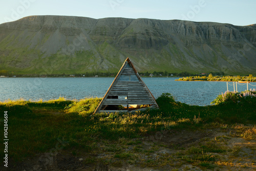 Small wooden hut on grassy shore in sundown photo