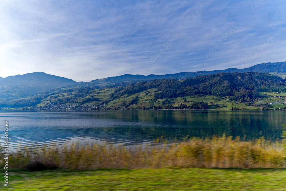 Scenic view of Lake Sarnen on a sunny autumn day with woodland and mountain panorama in the background. Photo taken October 17th, 2023, Sachseln, Canton Obwalden, Switzerland. Scenic view of Lake Sarnen on a sunny autumn day with woodland and mountain panorama in the background. Photo taken October 17th, 2023, Sachseln, Canton Obwalden, Switzerland.
