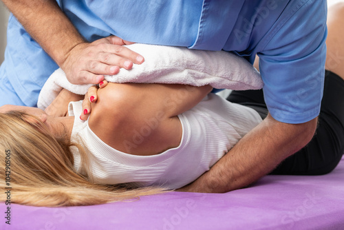 Chiropractor performing a spinal adjustment on a patient lying on a therapy table, focusing on realigning the spine to relieve back pain and improve mobility photo