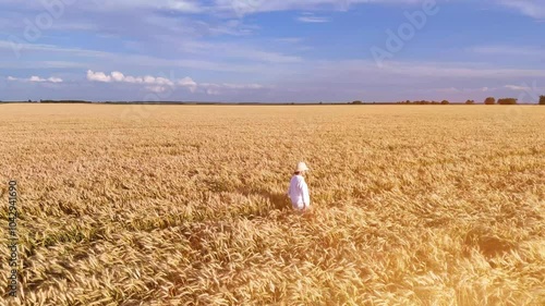 Girl in white dress walks and runs in field and wheat or cereal fields.