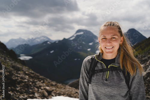 Portrait of smiling mid adult woman on mountain against cloudy sky photo