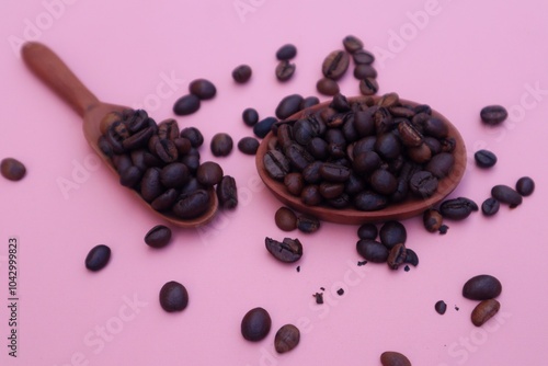 Robusta coffee beans or Coffea canephora in a wooden spoon and some scattered around it, close up view. photo