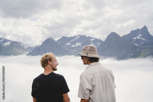 Rear view of friends talking while standing by cloudscape against mountains photo