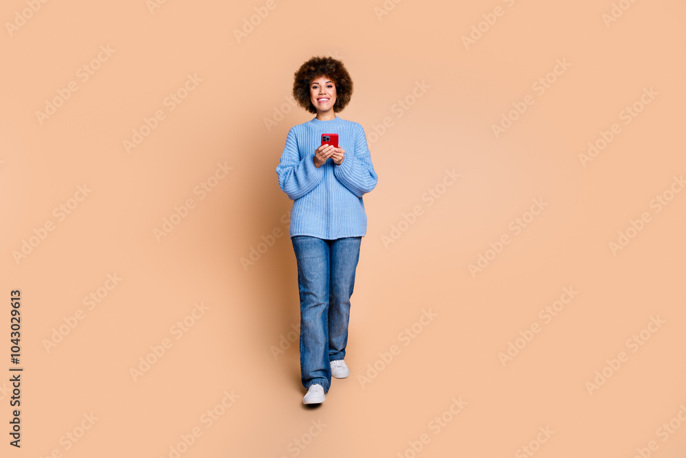 Full size photo of satisfied girl dressed blue knit sweater holding smartphone read email walking isolated on pastel color background Full size photo of satisfied girl dressed blue knit sweater holding smartphone read email walking isolated on pastel color background