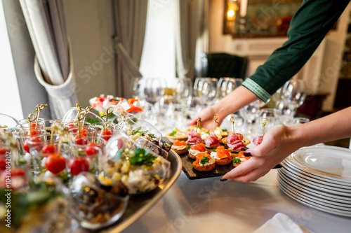 A close-up of a hand arranging gourmet appetizers on a table at an elegant event, showcasing a variety of colorful and beautifully presented dishes. Perfect for culinary, catering, or event themes. photo